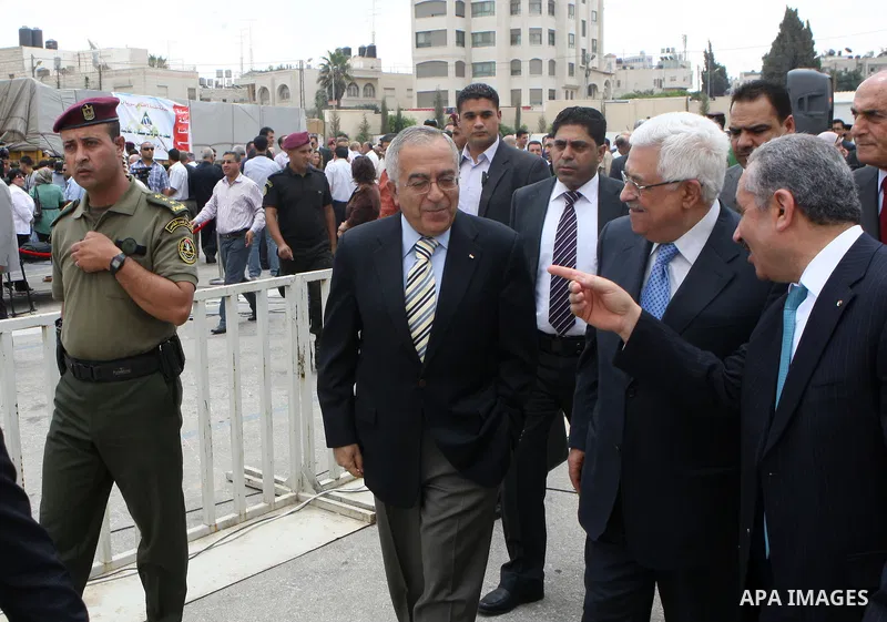 Palestinian President Mahmoud Abbas, os accompanied by other officials as he waves to a convoy of trucks carrying food and medical supplies, which reportedly were provided by the Palestinian people, leaving Ramallah boun...