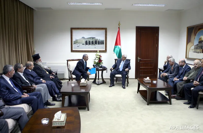 Palestinian President Mahmoud Abbas, os accompanied by other officials as he waves to a convoy of trucks carrying food and medical supplies, which reportedly were provided by the Palestinian people, leaving Ramallah boun...