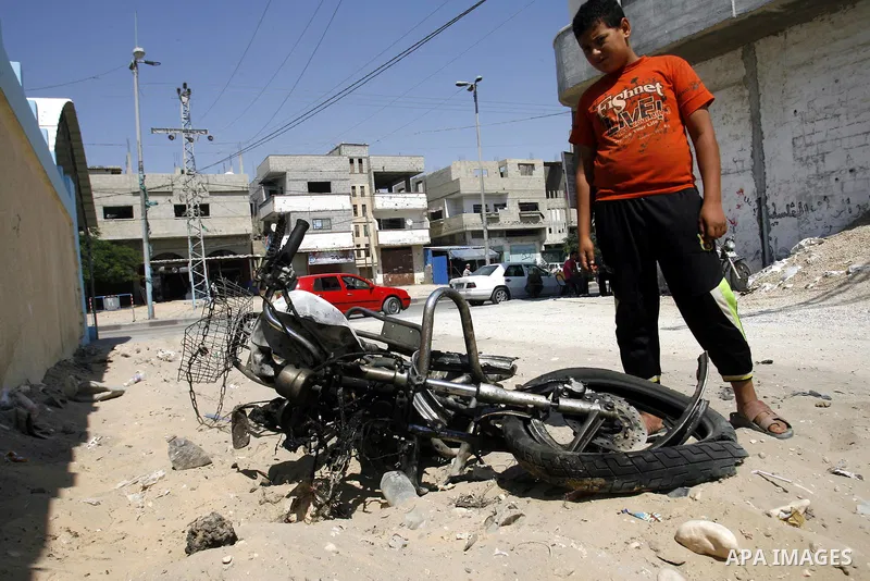 A Palestinian youth inspects the remains of motorcycle that was hit by an Israeli air strike in Rafah in the southern Gaza Strip August 5, 2012. An Israeli air strike killed a Palestinian gunman from a radical Islamist g...