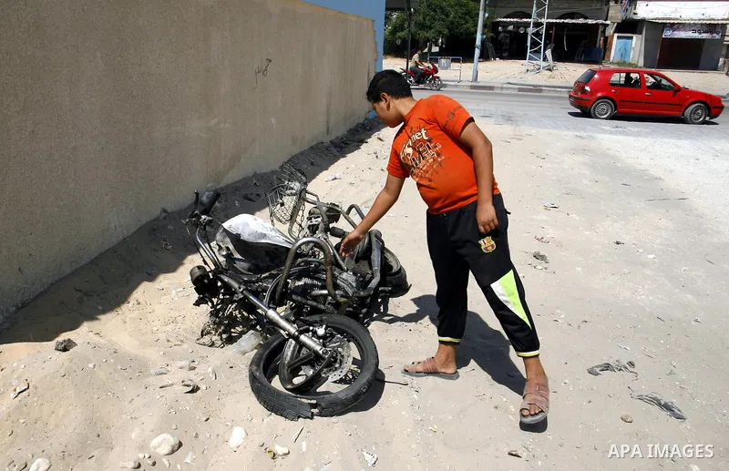 A Palestinian youth inspects the remains of motorcycle that was hit by an Israeli air strike in Rafah in the southern Gaza Strip August 5, 2012. An Israeli air strike killed a Palestinian gunman from a radical Islamist g...