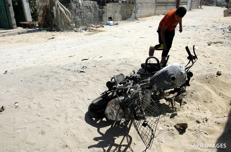 A Palestinian youth inspects the remains of motorcycle that was hit by an Israeli air strike in Rafah in the southern Gaza Strip August 5, 2012. An Israeli air strike killed a Palestinian gunman from a radical Islamist g...