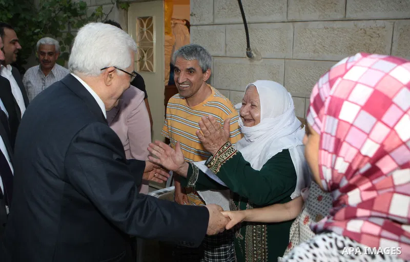 Palestinian President Mahmoud Abbas (Abu Mazen) speaks to a woman during a visit to a Palestinian indigent family, in the West Bank city of Ramallah on 06 August 2012. Photo by Thaer Ganaim