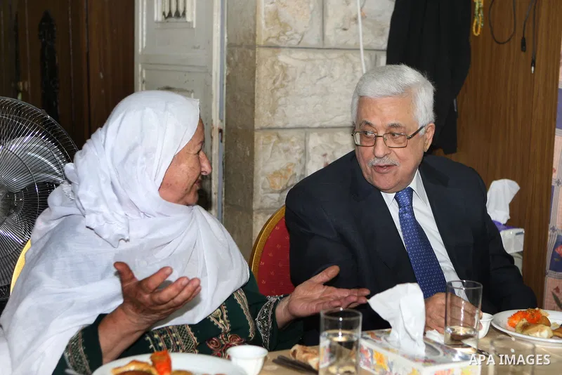 Palestinian President Mahmoud Abbas (Abu Mazen) speaks to a woman during a visit to a Palestinian indigent family, in the West Bank city of Ramallah on 06 August 2012. Photo by Thaer Ganaim