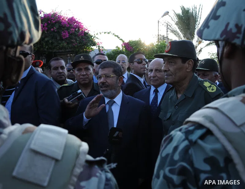 Egypt's President Mohamed Mursi gestures, while Field Marshal Hussein Tantawi, and an army general look on at a checkpoint in al-Arish August 6, 2012. Egypt branded Islamist gunmen who killed 16 police near the Israeli b...