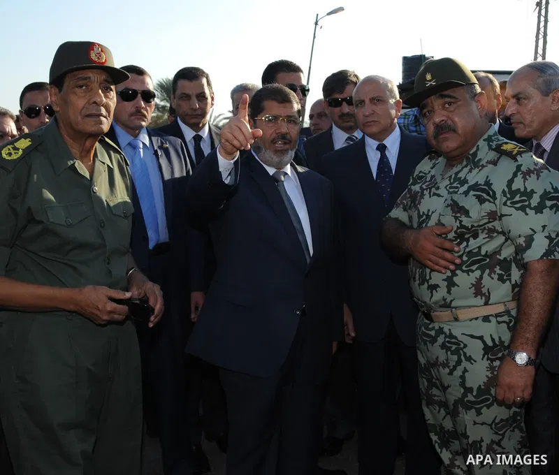 Egypt's President Mohamed Mursi gestures, while Field Marshal Hussein Tantawi, and an army general look on at a checkpoint in al-Arish August 6, 2012. Egypt branded Islamist gunmen who killed 16 police near the Israeli b...