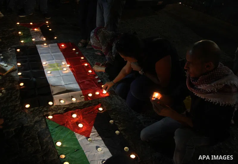 Palestinian youths light candles and place them on Palestinian and Egyptian flags on August 8, 2012, in the West Bank city of Ramallah, in memory of the 16 Egyptian soldiers who were killed in a militant ambush on August...