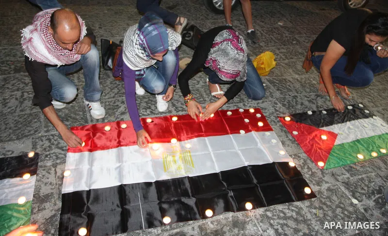 Palestinian youths light candles and place them on Palestinian and Egyptian flags on August 8, 2012, in the West Bank city of Ramallah, in memory of the 16 Egyptian soldiers who were killed in a militant ambush on August...