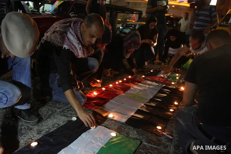 Palestinian youths light candles and place them on Palestinian and Egyptian flags on August 8, 2012, in the West Bank city of Ramallah, in memory of the 16 Egyptian soldiers who were killed in a militant ambush on August...