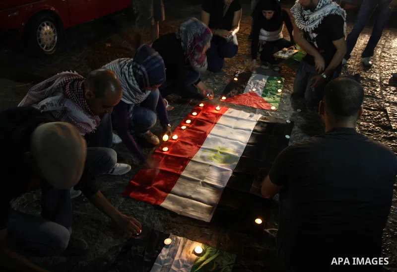 Palestinian youths light candles and place them on Palestinian and Egyptian flags on August 8, 2012, in the West Bank city of Ramallah, in memory of the 16 Egyptian soldiers who were killed in a militant ambush on August...