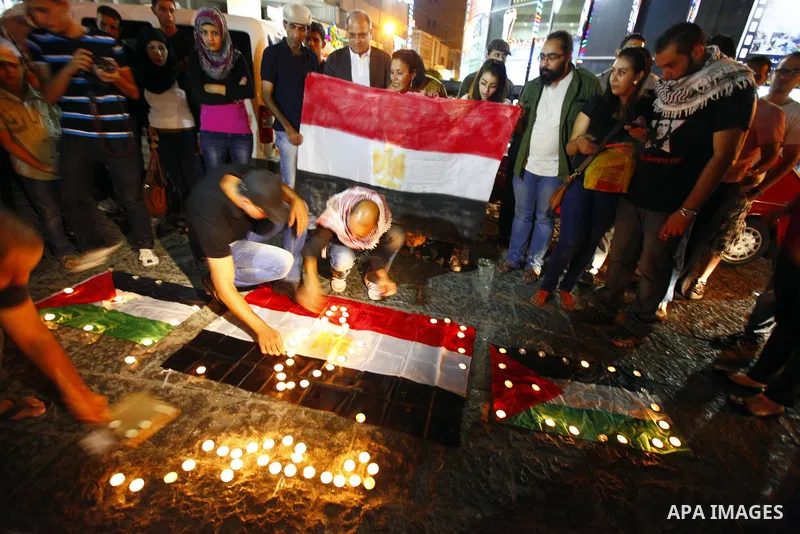 Palestinian youths light candles and place them on Palestinian and Egyptian flags on August 8, 2012, in the West Bank city of Ramallah, in memory of the 16 Egyptian soldiers who were killed in a militant ambush on August...