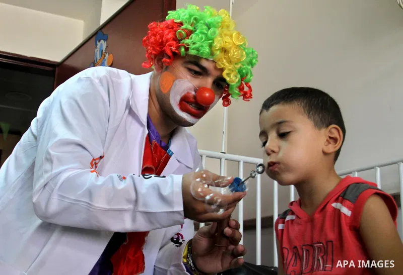 A Palestinian doctor dressed as clown, plays with a child during a physiological treatment session at a hospital in the West Bank city of Nablus, on Aug. 09, 2012. Photo by Nedal Eshtayah