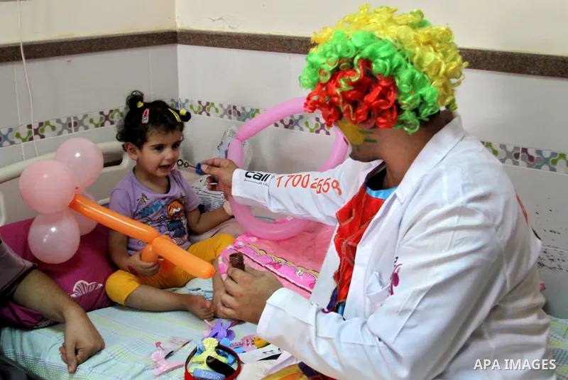A Palestinian doctor dressed as clown, plays with a child during a physiological treatment session at a hospital in the West Bank city of Nablus, on Aug. 09, 2012. Photo by Nedal Eshtayah