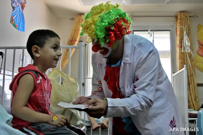 A Palestinian doctor dressed as clown, plays with a child during a physiological treatment session at a hospital in the West Bank city of Nablus, on Aug. 09, 2012. Photo by Nedal Eshtayah