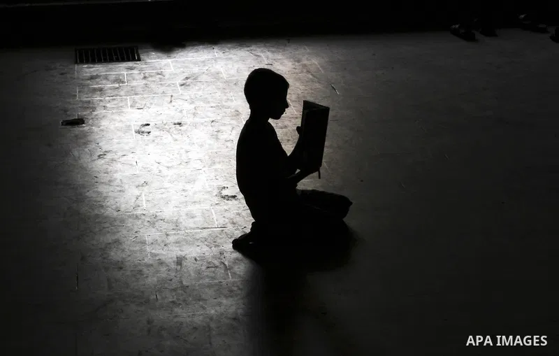 A Palestinian boy is silhouetted against the reflection of a window in the floor of the Al-Omari mosque as he reads in a copy of the Holy Koran during prayers in the Gaza Strip, 09 August 2012. Muslims throughout the wor...