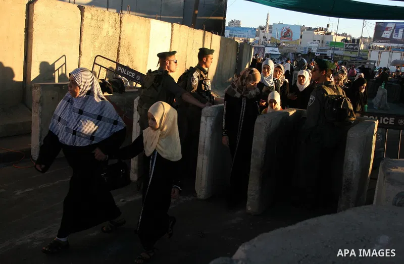 Israeli border police officers watch Palestinians crossing at the military checkpoint of Qalandia, North of Jerusalem, in the West Bank, 10 August 2012, on their way to Jerusalem to attend the Ramadan Friday Prayers in t...