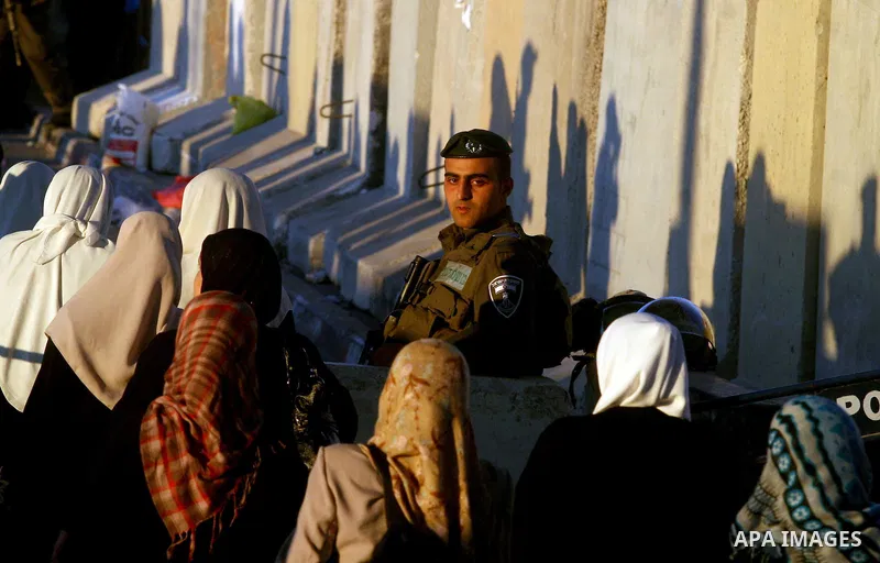 Israeli border police officers watch Palestinians crossing at the military checkpoint of Qalandia, North of Jerusalem, in the West Bank, 10 August 2012, on their way to Jerusalem to attend the Ramadan Friday Prayers in t...