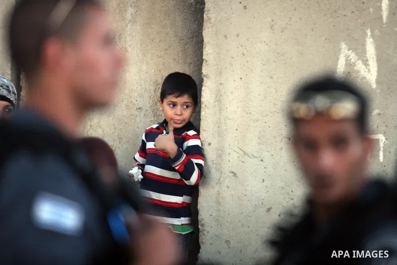 A Palestinian child waits next to the separation barrier to cross at the military checkpoint of Qalandia, North of Jerusalem, in the West Bank, 10 August 2012, on their way to Jerusalem to attend the Ramadan Friday Praye...