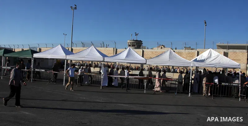 Palestinian men wait in line to cross at the military checkpoint of Qalandia, North of Jerusalem, in the West Bank, 10 August 2012, on their way to Jerusalem to attend the Ramadan Friday Prayers in the Al-Aqsa Mosque. Is...