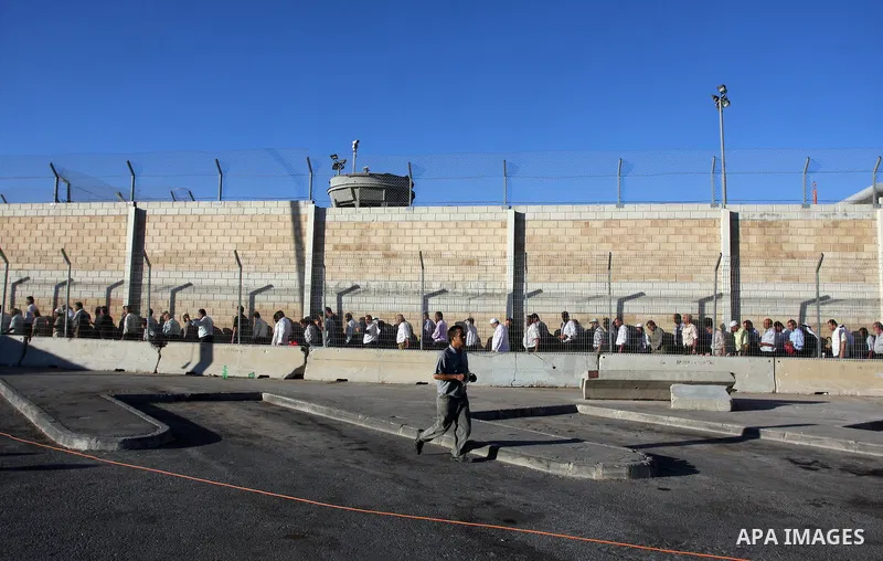 Palestinian men wait in line to cross at the military checkpoint of Qalandia, North of Jerusalem, in the West Bank, 10 August 2012, on their way to Jerusalem to attend the Ramadan Friday Prayers in the Al-Aqsa Mosque. Is...