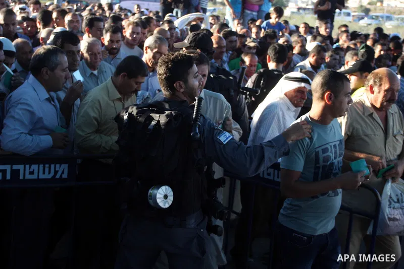 Israeli border police officers check Palestinian men ID while crossing at the military checkpoint of Qalandia, North of Jerusalem, in the West Bank, 10 August 2012, on their way to Jerusalem to attend the Ramadan Friday...