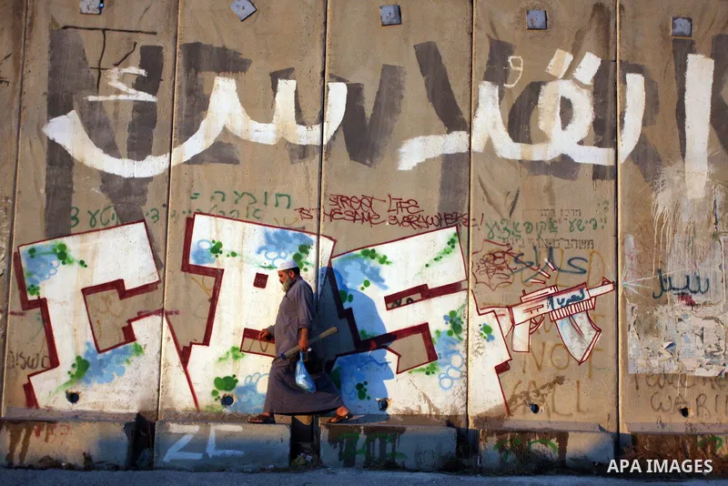 Palestinian Muslims walk next to the Israeli separation wall with ''Jerusalem'' written in Arabic on it to cross the Qalandia checkpoint, located near West Bank City of Ramallah, Palestine, Aug. 10, 2012. The Palestinian...