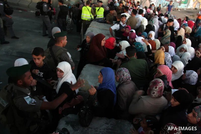 Israeli border police officers check Palestinian women ID while crossing at the military checkpoint of Qalandia, North of Jerusalem, in the West Bank, 10 August 2012, on their way to Jerusalem to attend the Ramadan Frida...