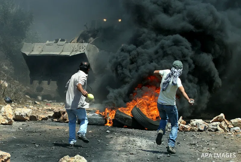 Palestinian protesters throw stones at Israeli bulldozer during a demonstration against the expropriation of Palestinian land by Israel in the village of Kafr Qaddum, near the West Bank city of Nablus, on August 10, 2012...