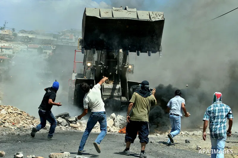 Palestinian protesters throw stones at Israeli bulldozer during a demonstration against the expropriation of Palestinian land by Israel in the village of Kafr Qaddum, near the West Bank city of Nablus, on August 10, 2012...