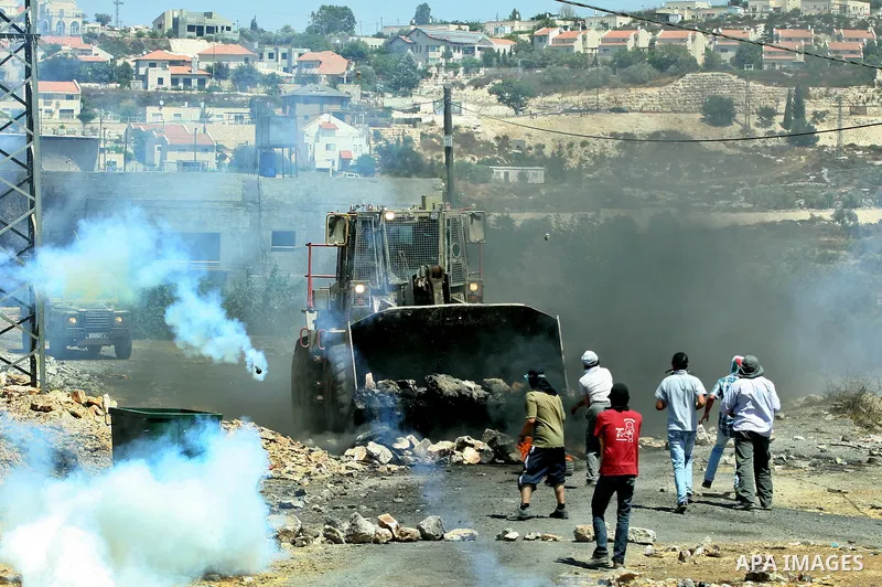 Palestinian protesters throw stones at Israeli bulldozer during a demonstration against the expropriation of Palestinian land by Israel in the village of Kafr Qaddum, near the West Bank city of Nablus, on August 10, 2012...