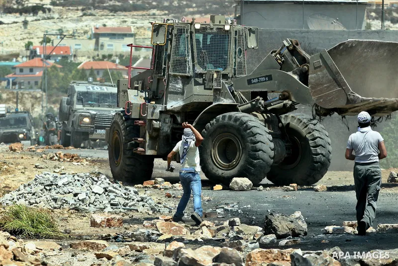 Palestinian protesters throw stones at Israeli bulldozer during a demonstration against the expropriation of Palestinian land by Israel in the village of Kafr Qaddum, near the West Bank city of Nablus, on August 10, 2012...