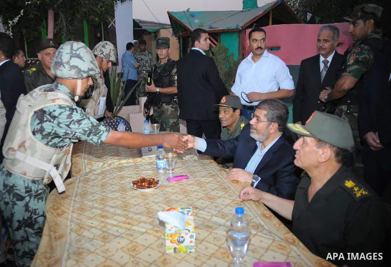 Egypt's new Islamist President Mohamed Mursi (C), Field Marshal Hussein Tantawi (L) and Egyptian Armed Forces Chief of Staff Sami Anan (R) shake hands with a soldier at a checkpoint in al-Arish August 10, 2012. Egypt bra...