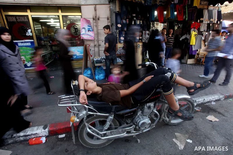 A Palestinian youth sleeps on his motorcycle at a market in Gaza city on Aug 13,2012, as Muslims over the world prepare to celebrate Eid al-Fitr, a three day holiday marking the end of the religious month of Ramadan in w...