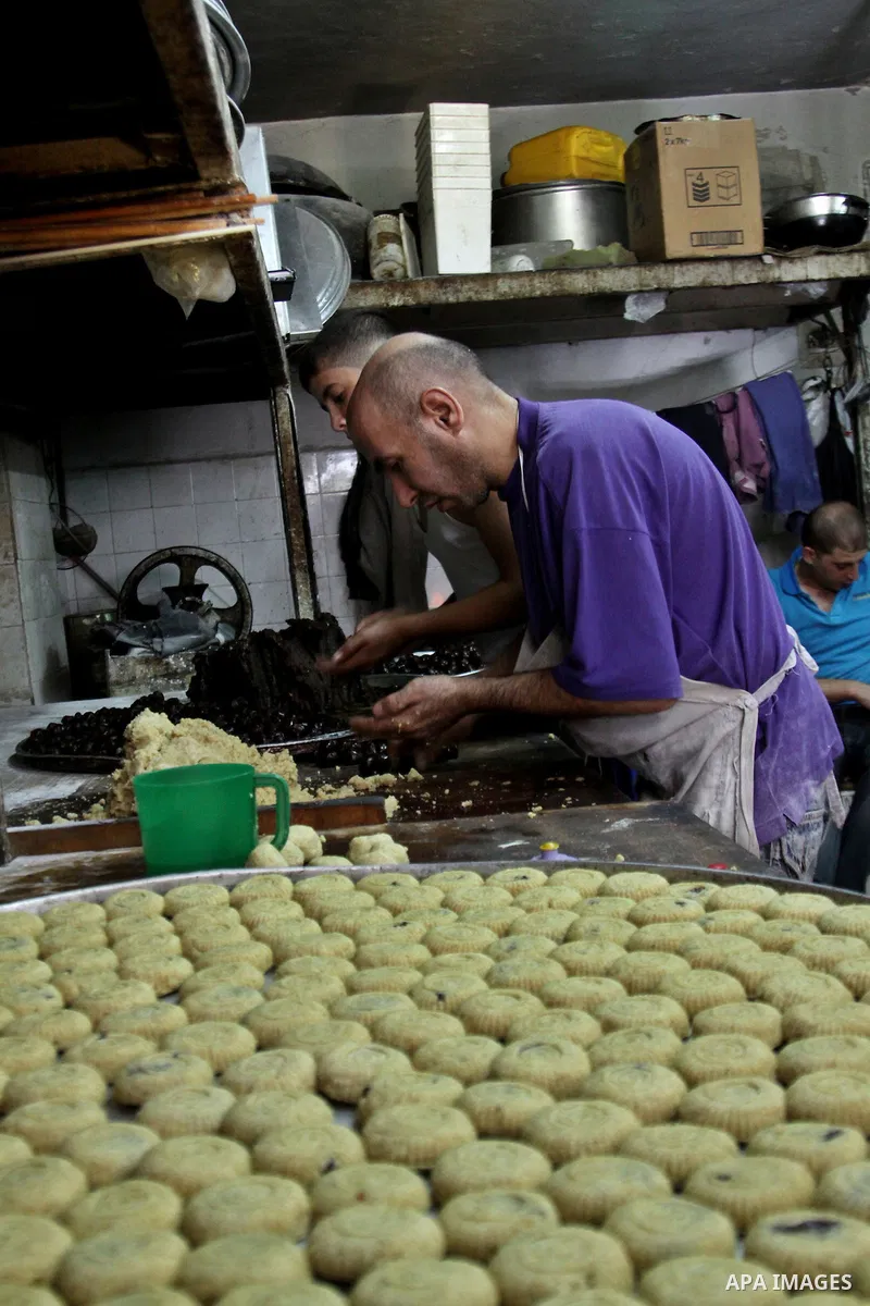 Palestinians vendor make traditional nut cookies before the upcoming Eid al-Fitr holidays at a bakery in the West Bank city of Nablus, on Aug. 14, 2012. Muslims will celebrate Eid al-Fitr that marks the end of the fastin...