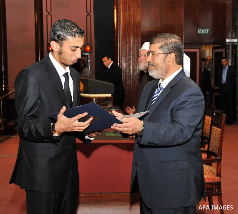 Egypt's President Mohamed Mursi, presents a prize to a youth who won the Conservation of the Holy Koran contest during the Laylat al-Qadr at Egypt Al-Azhar Conference Center at Nasr City in Cairo August 12, 2012. Egypt's...