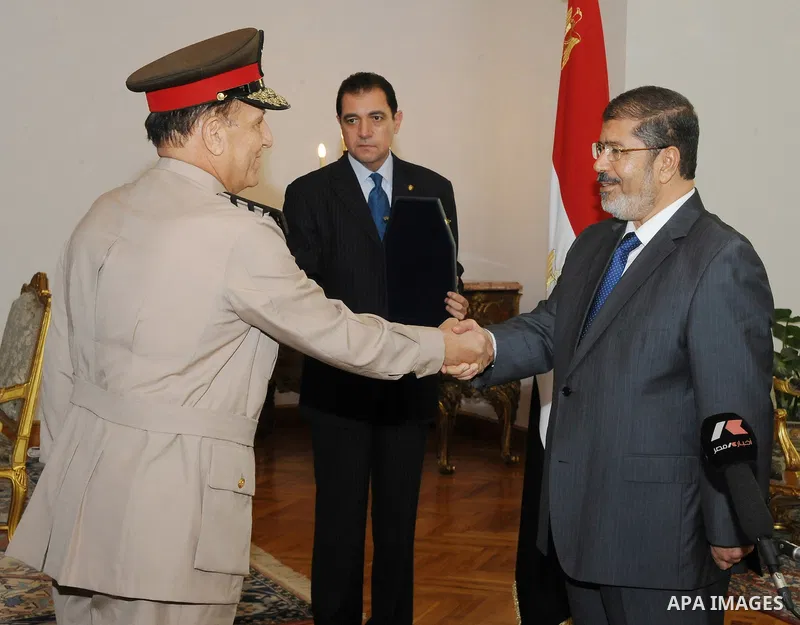 Former Armed Forces Chief of Staff Sami Anan, left, shakes hands with Egyptian President Mohammed Morsi at the Presidential Palace in Cairo, Egypt, Tuesday, Aug. 14, 2012. Egypt's president has given awards to the nation...