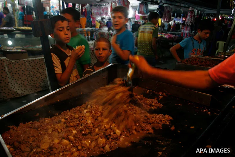 Palestinian children eat meat sandwiches at a market in the southern Gaza strip town of Rafah on Aug 16,2012, as Muslims over the world prepare to celebrate Eid al-Fitr, a three day holiday marking the end of the religio...