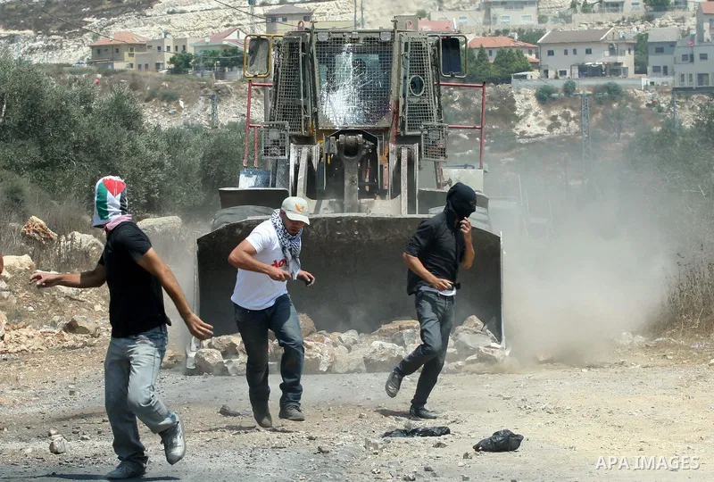 Palestinian protesters throw stones at Israeli bulldozer during a demonstration against the expropriation of Palestinian land by Israel in the village of Kfar Qaddum, near the West Bank city of Nablus, on August 17, 2012...