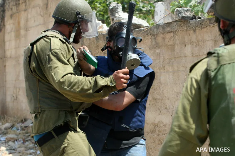 An Israeli soldier hits a Palestinian press photographer during a demonstration against the expropriation of Palestinian land by Israel in the village of Kfar Qaddum, near the West Bank city of Nablus, on August 17, 2012...