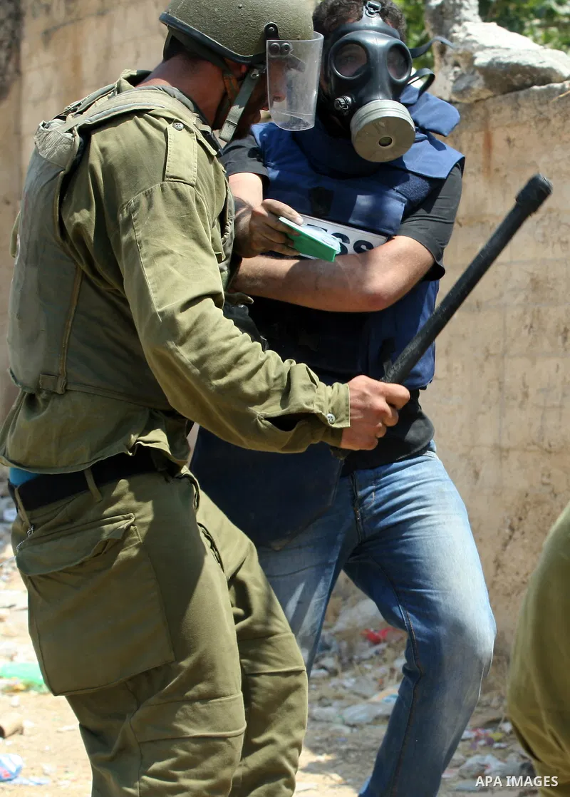 An Israeli soldier hits a Palestinian press photographer during a demonstration against the expropriation of Palestinian land by Israel in the village of Kfar Qaddum, near the West Bank city of Nablus, on August 17, 2012...