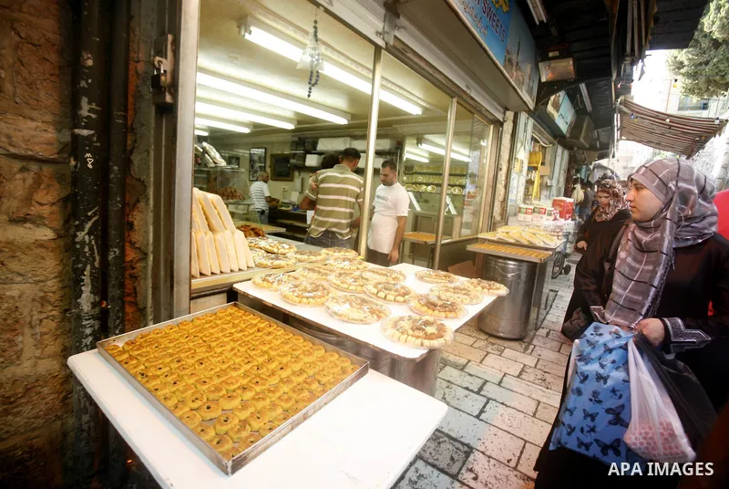 A Palestinian woman buys cake at the market during preparations for the Eid Al-Fitr feast in Jerusalem's Old City on Aug 16, 2012, as Muslims over the world prepare to celebrate Eid al-Fitr, a three day holiday marking t...