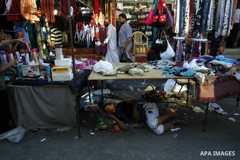 A Palestinian vendor sleeps under his goods in the market during preparations for the Eid Al-Fitr feast in Rafah in the southern of Gaza strip on Aug 16, 2012, as Muslims over the world prepare to celebrate Eid al-Fitr,...