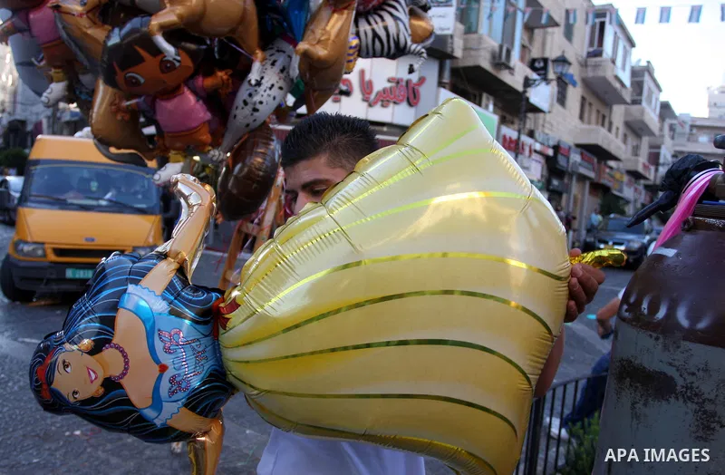A Palestinian vendor sells ballons in the market during preparations for the Eid Al-Fitr feast in the West Bank city of Ramallah, on Aug 16, 2012, as Muslims over the world prepare to celebrate Eid al-Fitr, a three day h...