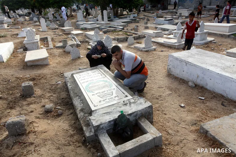 Palestinians visit their relative's graves at a cemetery in Gaza City on the first day of Eid Al-Fitr on Aug. 19, 2012. Eid-Al-Fitr marks the end of the Muslim holy month of Ramadhan. Photo by Ashraf Amra