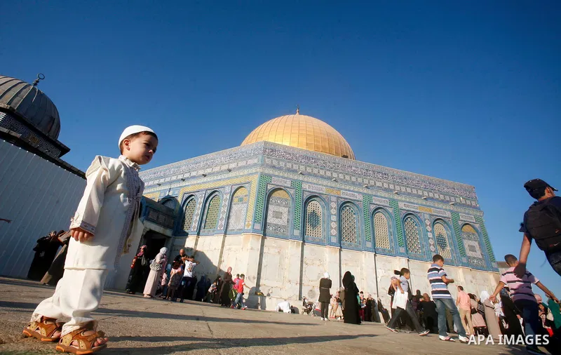 Palestinian boy plays in front of the Dome of the Rock mosque during the Eid al-Fitr prayers at al-Aqsa mosque in Jerusalem's Old City, Sunday, Aug. 19, 2012. Muslims are celebrating the festival of Eid al-Fitr which mar...