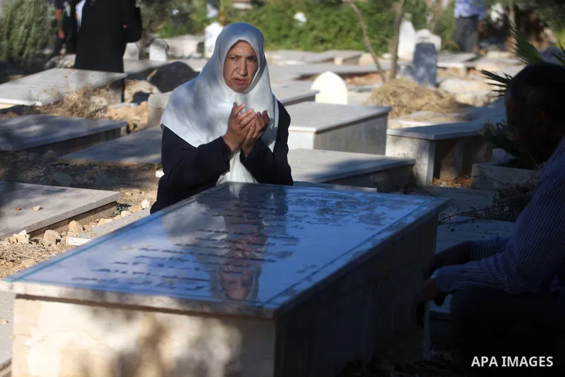 An elderly Palestinian prays next to a grave in a cemetery as part of the Eid al-Fitr traditions in the West Bank city of Ramallah, Sunday, Aug. 19, 2012. Muslims are celebrating the festival of Eid al-Fitr which marks t...