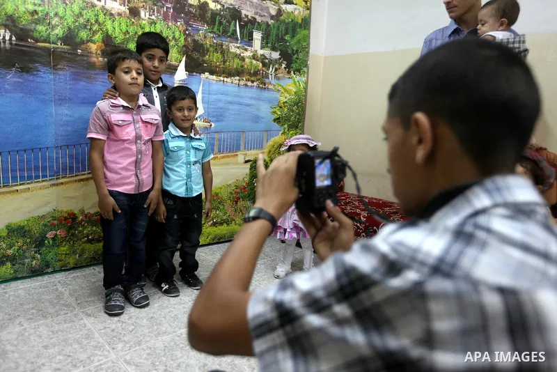 A Palestinian photographer take pictures for children in his studio in Gaza city during the first day of Eid al-Fitr which marks the end of the Muslim fasting month of Ramadan, Sunday, Aug. 19, 2012. Eid, one of the most...