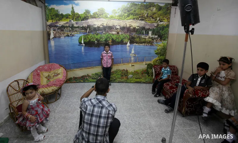 A Palestinian photographer take pictures for children in his studio in Gaza city during the first day of Eid al-Fitr which marks the end of the Muslim fasting month of Ramadan, Sunday, Aug. 19, 2012. Eid, one of the most...