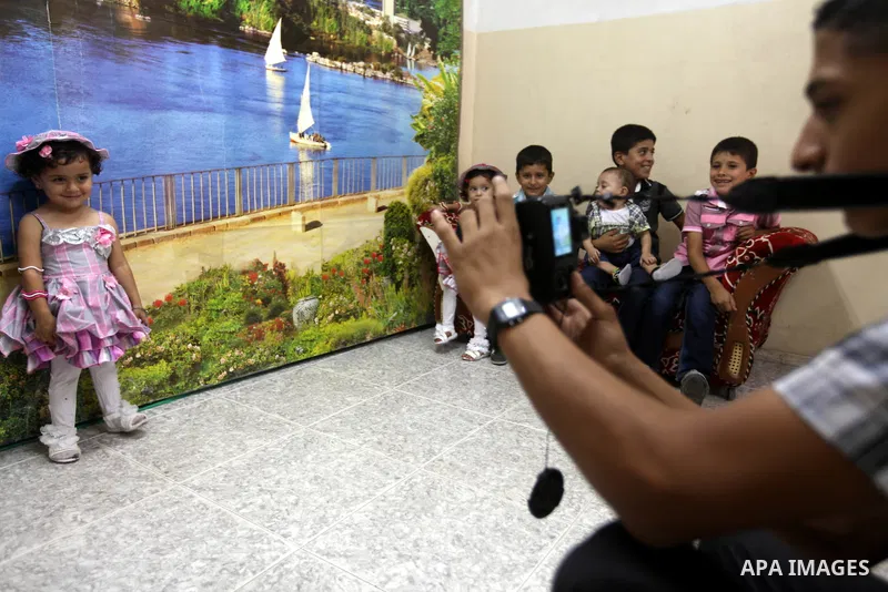 A Palestinian photographer take pictures for children in his studio in Gaza city during the first day of Eid al-Fitr which marks the end of the Muslim fasting month of Ramadan, Sunday, Aug. 19, 2012. Eid, one of the most...