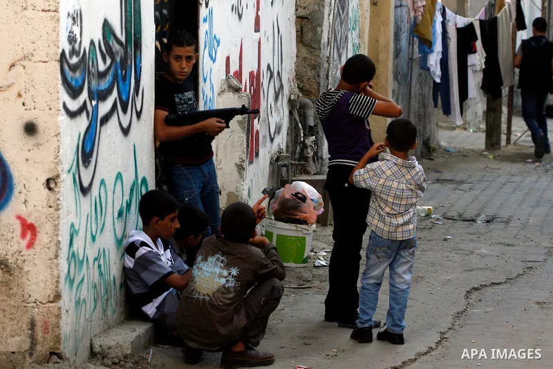 Palestinian children play with a gun toy on the Second day of Eid al-Fitr in Rafah in the southern of Gaza strip, Aug. 20, 2012. which marks the end of the Muslim fasting month of Ramadan. Eid, one of the most important...