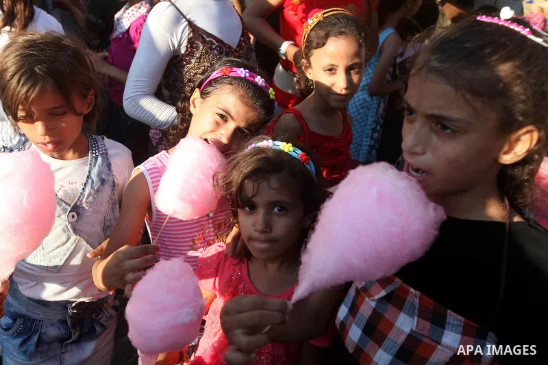 Palestinian children eat cotton candy at a park during the Second day of Eid al-Fitr in Gaza city, Aug. 20, 2012. which marks the end of the Muslim fasting month of Ramadan. Eid, one of the most important holidays in the...